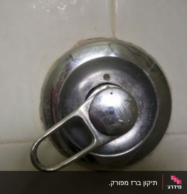 ברז מים עגול עם ידית מתכת על קיר קרמיקה